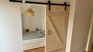 A bedroom with a bed, a hanging light fixture, and a wooden door.