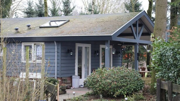 Ein Haus mit schrägem Dach, einer Veranda und einem kleinen Garten.