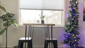 A corner room with a window, two black stools, a potted plant, and a Christmas tree with lights. - Contemporary 2 Bedrooms Super location (Anchorage)