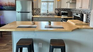 A modern kitchen with a central island, pendant lighting, and patterned backsplash. - Contemporary 2 Bedrooms Super location (Anchorage)
