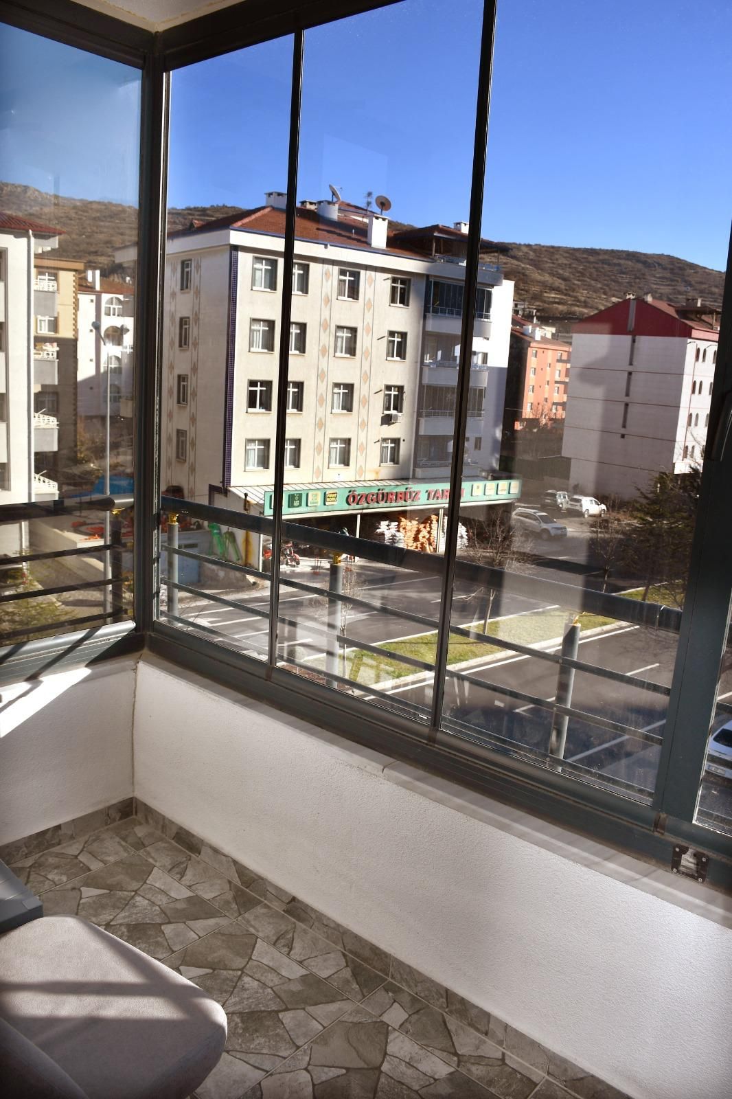 A room with a large window overlooking a parking area and buildings.
