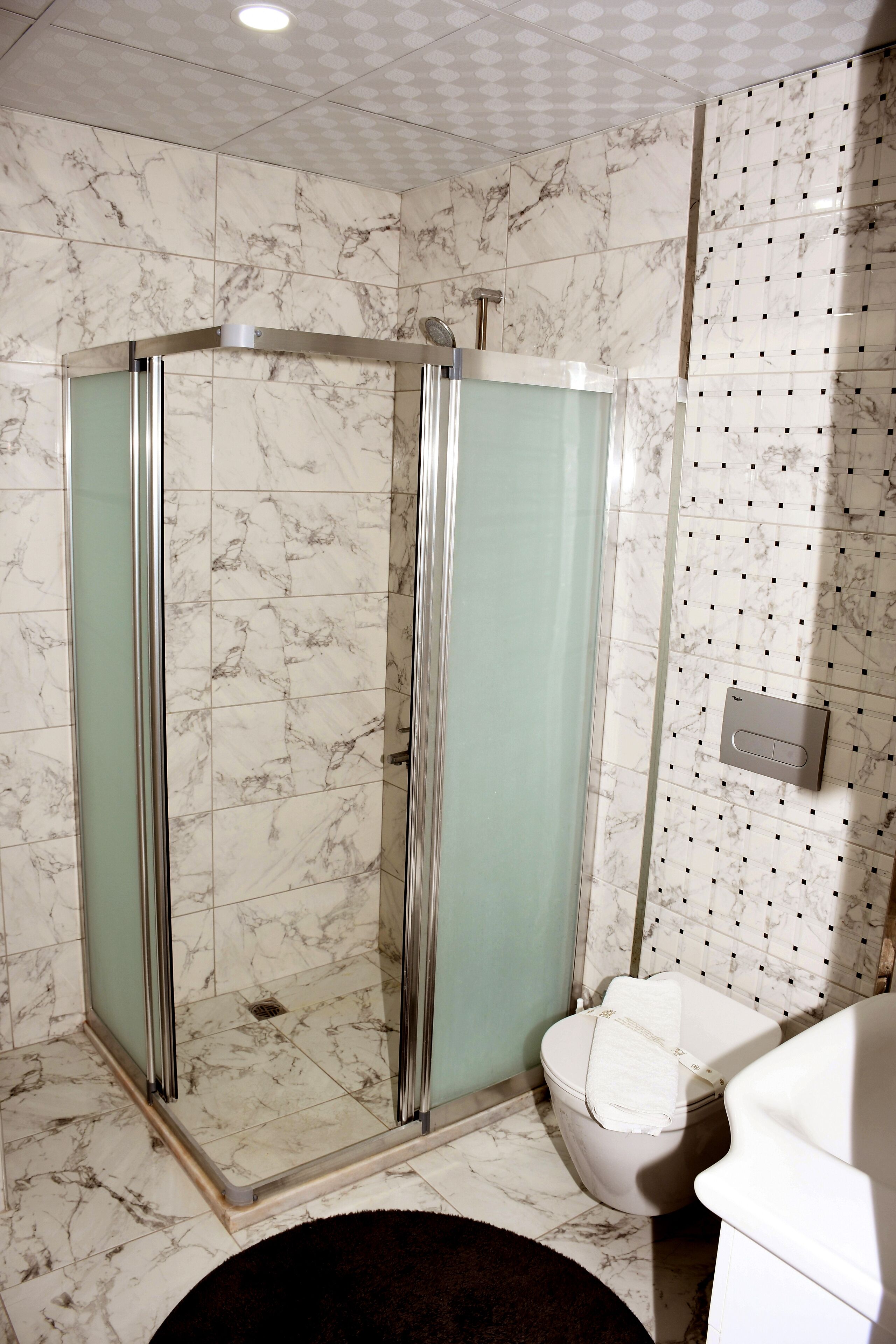 Bany amb dutxa tancada amb vidre, vàter i un lavabo.
