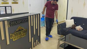 A reception area with a reception desk, clocks, and a person cleaning the floor.