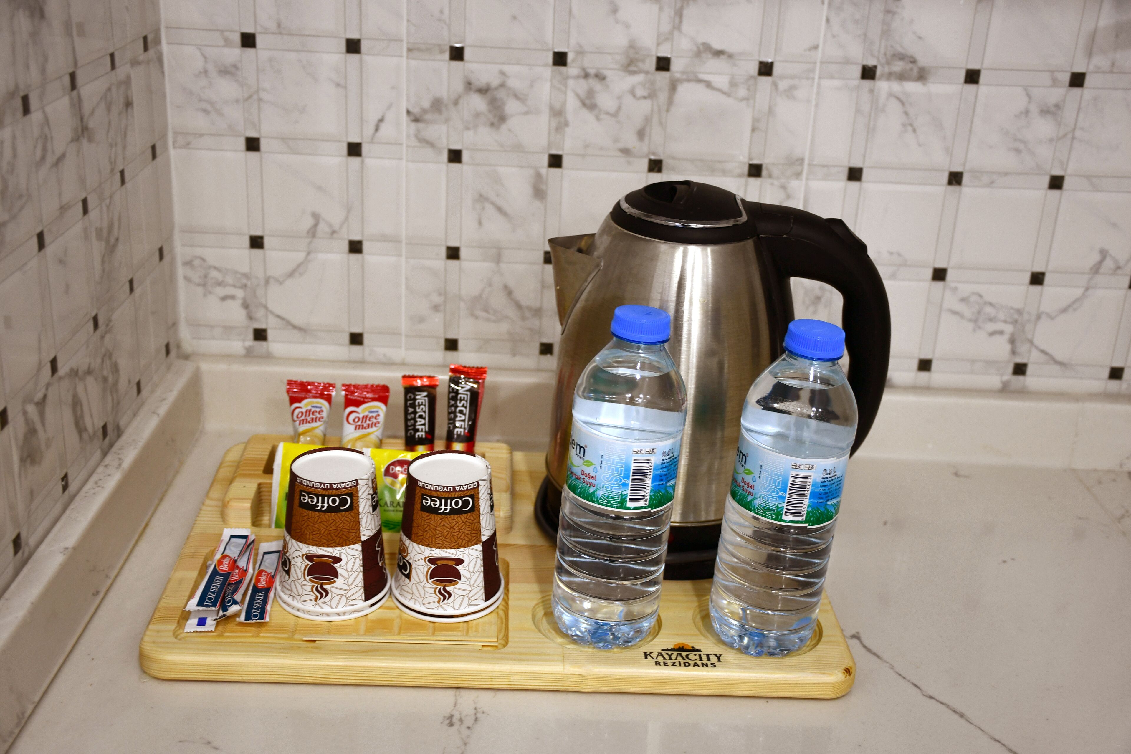 A kitchen counter with a coffee maker, two bottles of water, and several coffee pods.
