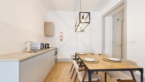 A modern kitchen with white cabinets, a wooden countertop, a built-in microwave, and a hanging light fixture. - Colosseum Building - Apartment Gamma (Lisbon)