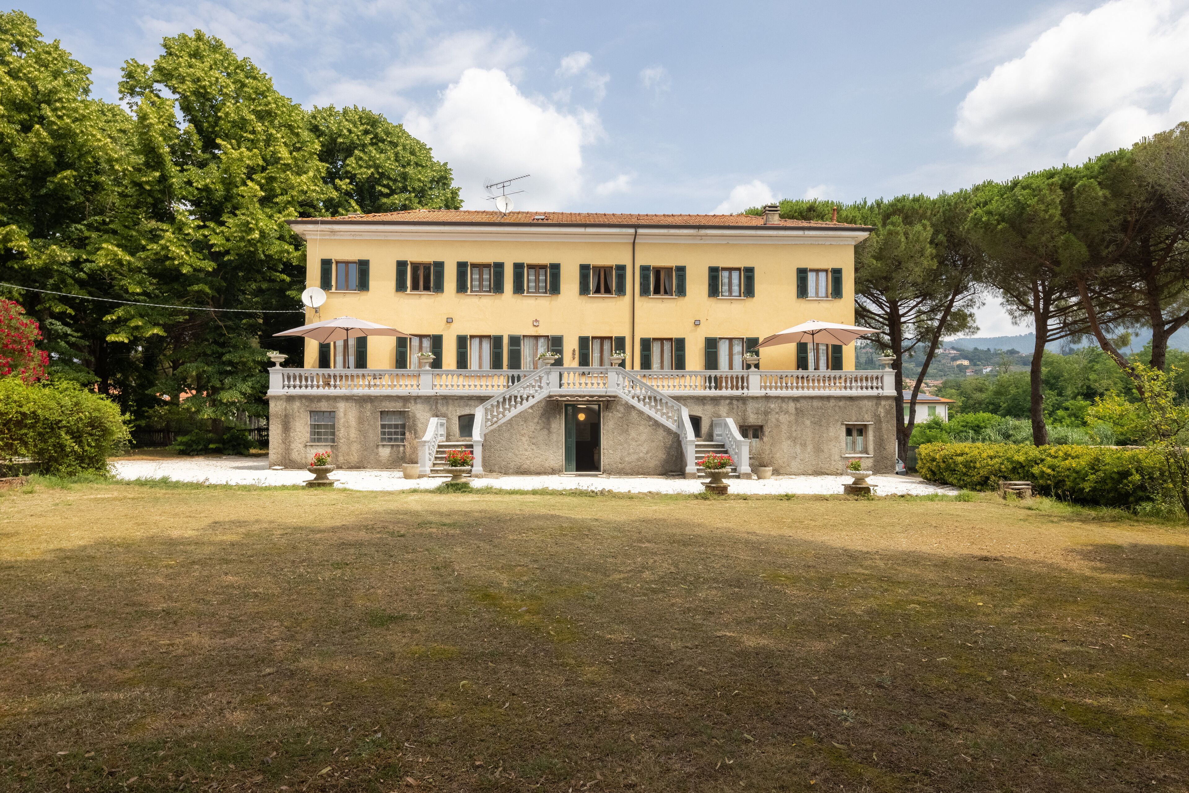A two-story building with a central staircase, a balcony, and a well-maintained lawn.