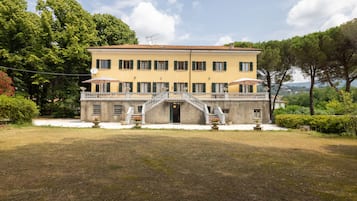 A two-story building with a central staircase, a balcony, and a well-maintained lawn.