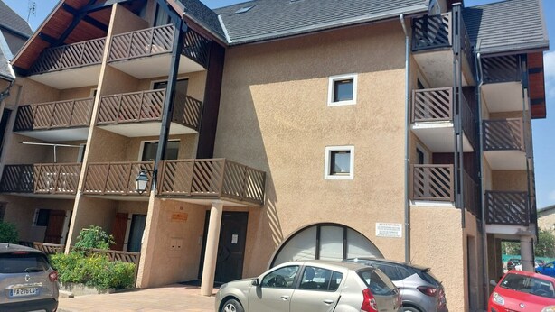 A multi-story building with balconies, a car parked in front, and a clear sky. - Cozy apartment in Autrans center, 4 pers, south terrace, pets allowed (Autrans-Méaudre en Vercors-Autrans)