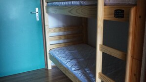 A bunk bed with a wooden frame and a mattress. - Cozy apartment in Autrans center, 4 pers, south terrace, pets allowed (Autrans-Méaudre en Vercors-Autrans)
