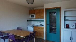 A compact kitchen with wooden cabinets, a microwave, a sink, and a teal door. - Cozy apartment in Autrans center, 4 pers, south terrace, pets allowed (Autrans-Méaudre en Vercors-Autrans)