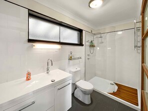 A modern bathroom with a white sink, toilet, and shower.