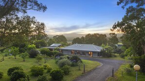 A building with a paved driveway, surrounded by greenery and trees. - Martha's Homestead - A relaxing Lovedale getaway (Lovedale)