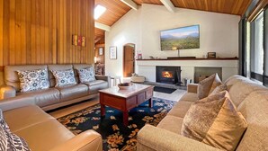 A cozy living room with a fireplace, leather sofas, and a large TV mounted on the wall. - Martha's Homestead - A relaxing Lovedale getaway (Lovedale)