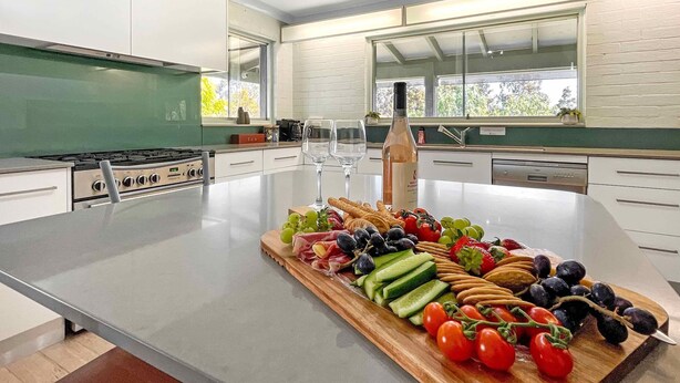 A modern kitchen with a large island, white cabinetry, and a window with a view. - Martha's Homestead - A relaxing Lovedale getaway (Lovedale)
