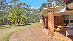 A covered outdoor area with a brick structure, a gravel path, and a lawn with palm trees. - Home Among the Gum Trees - Lovedale (Lovedale)