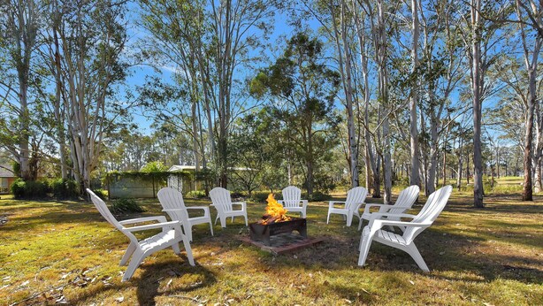 An outdoor seating area with white plastic chairs arranged around a fire pit. - Home Among the Gum Trees - Lovedale (Lovedale)