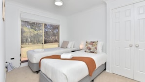 A bedroom with two beds, a window with a view of trees, a door, and a light fixture on the ceiling. - Home Among the Gum Trees - Lovedale (Lovedale)