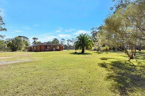 A large brick building with a flat roof, surrounded by a well-maintained grassy area and trees.