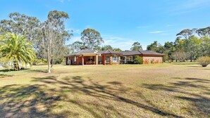 A two-story brick house with a front porch and a large lawn. - Home Among the Gum Trees - Lovedale (Lovedale)