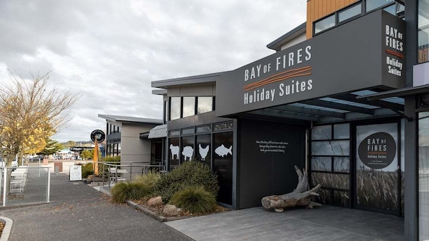 En modern byggnad med en skylt som visar texten ”Bay of Fires Holiday Suites”.