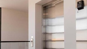 Un ascensor moderno con acabado metálico y un panel de control en la pared.
