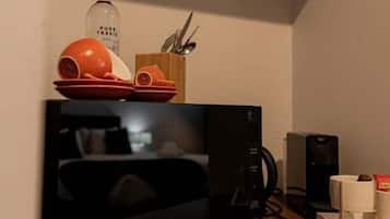 A kitchen with an LG microwave, a coffee maker, and a shelf with dishes and utensils.
