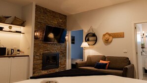 Una habitación acogedora con chimenea de piedra, televisión de pantalla plana, sofá y lámpara.