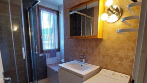 A compact bathroom with a glass shower enclosure, a sink, and a washing machine. - Cozy 3* apartment for 6, near slopes, with parking (Autrans-Méaudre en Vercors-Autrans)