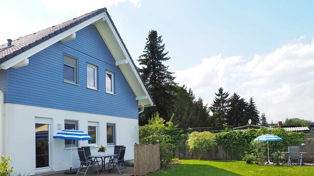 Une maison à deux étages, avec une façade bleue et un patio couvert.