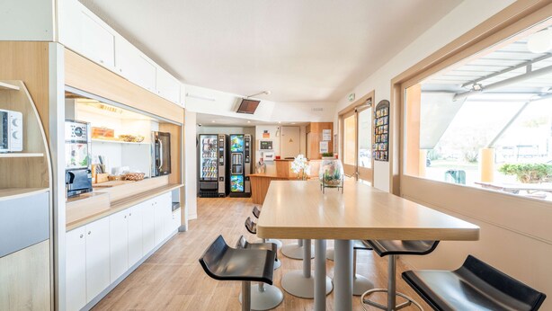 Una cocina moderna con encimera de madera, electrodomésticos integrados y una zona de estar con taburetes de bar.