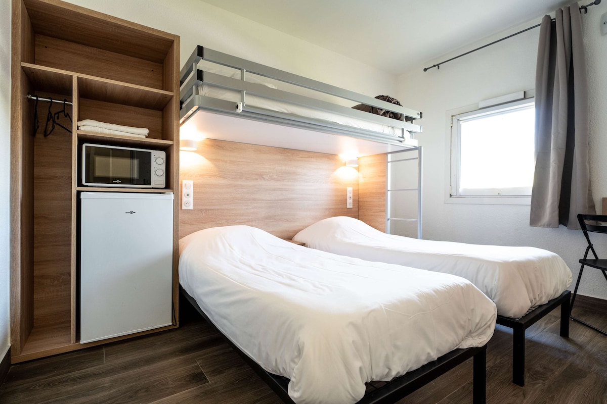 A compact room with two beds, a microwave, and a small refrigerator.