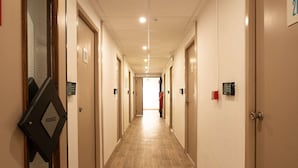Un pasillo de hotel con piso de madera, puertas a ambos lados y un cartel en la pared izquierda.