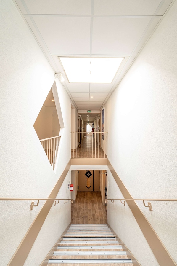 A modern hotel interior with a central staircase, a skylight, and a view of the hallway. - Kyriad Direct Brignoles - Provence Verte (Brignoles)