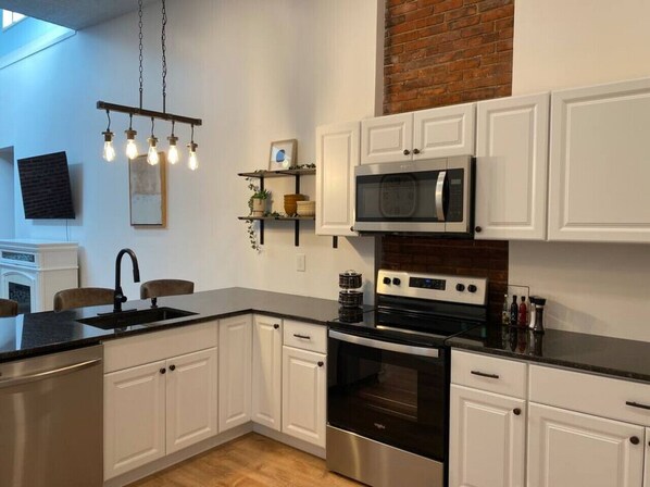 A modern kitchen with white cabinets, a stainless steel stove, and a black countertop.