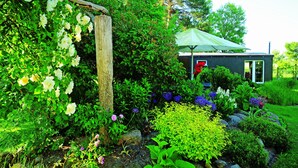 A garden with a variety of plants and flowers, a wooden structure, and a small building with a door and windows. - Vacation between nature and design (Ribnitz-Damgarten)
