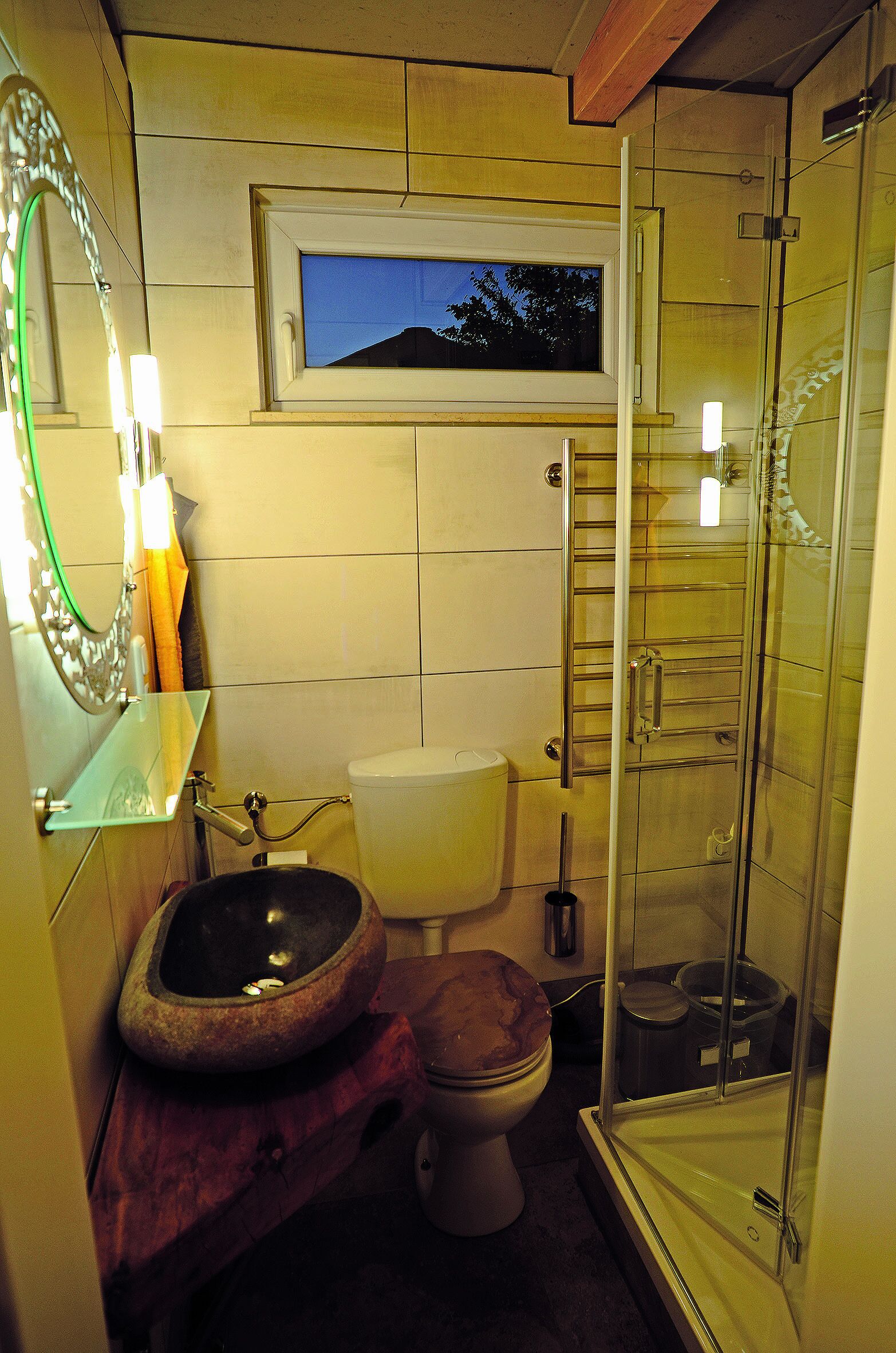 A bathroom with a glass shower enclosure, a toilet, and a sink with a stone basin.