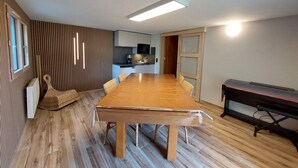 A modern kitchen with a large island, wooden flooring, and a dining area with a long table.