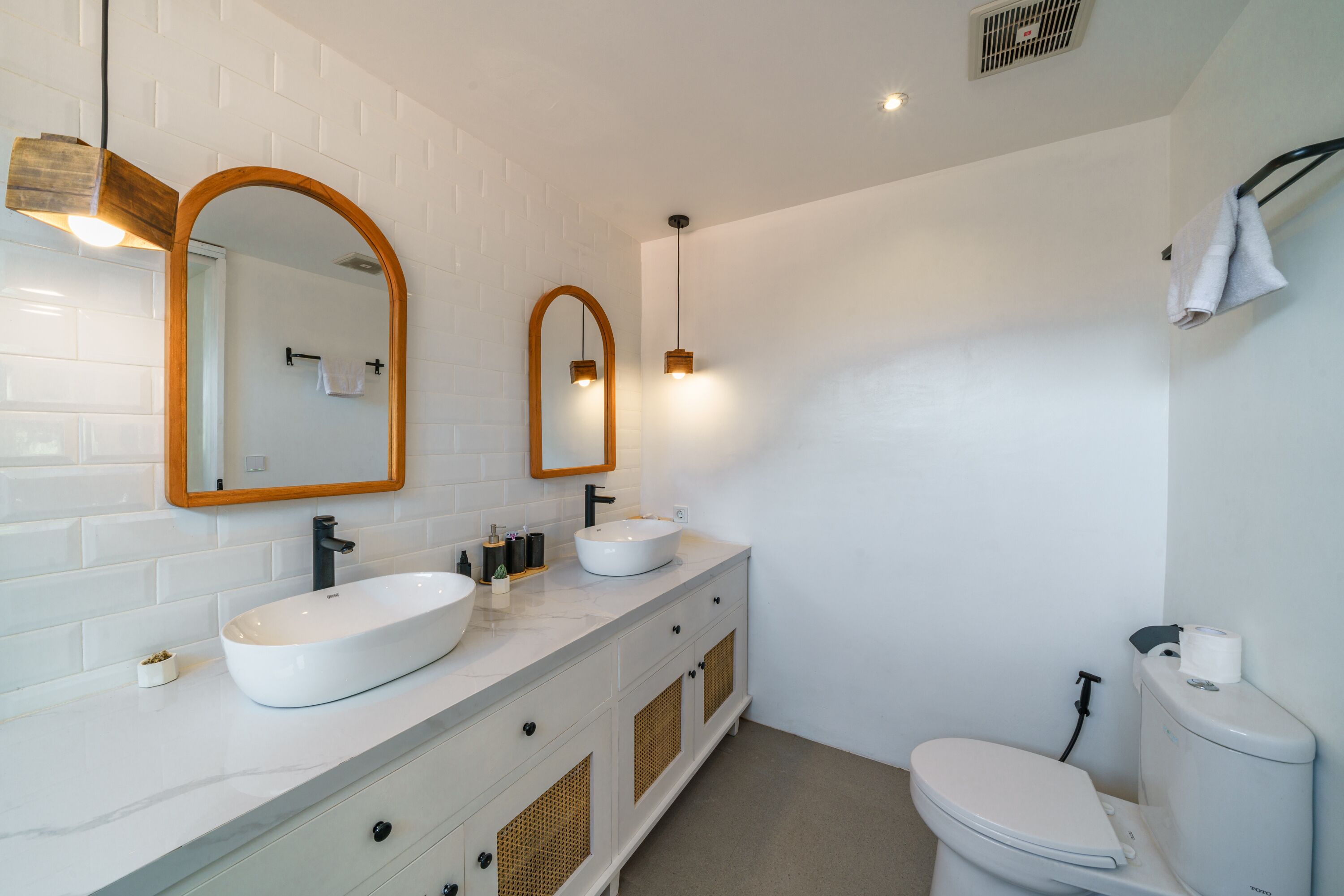 Ein modernes Badezimmer mit zwei Waschbecken, einer Toilette und einem Spiegel.