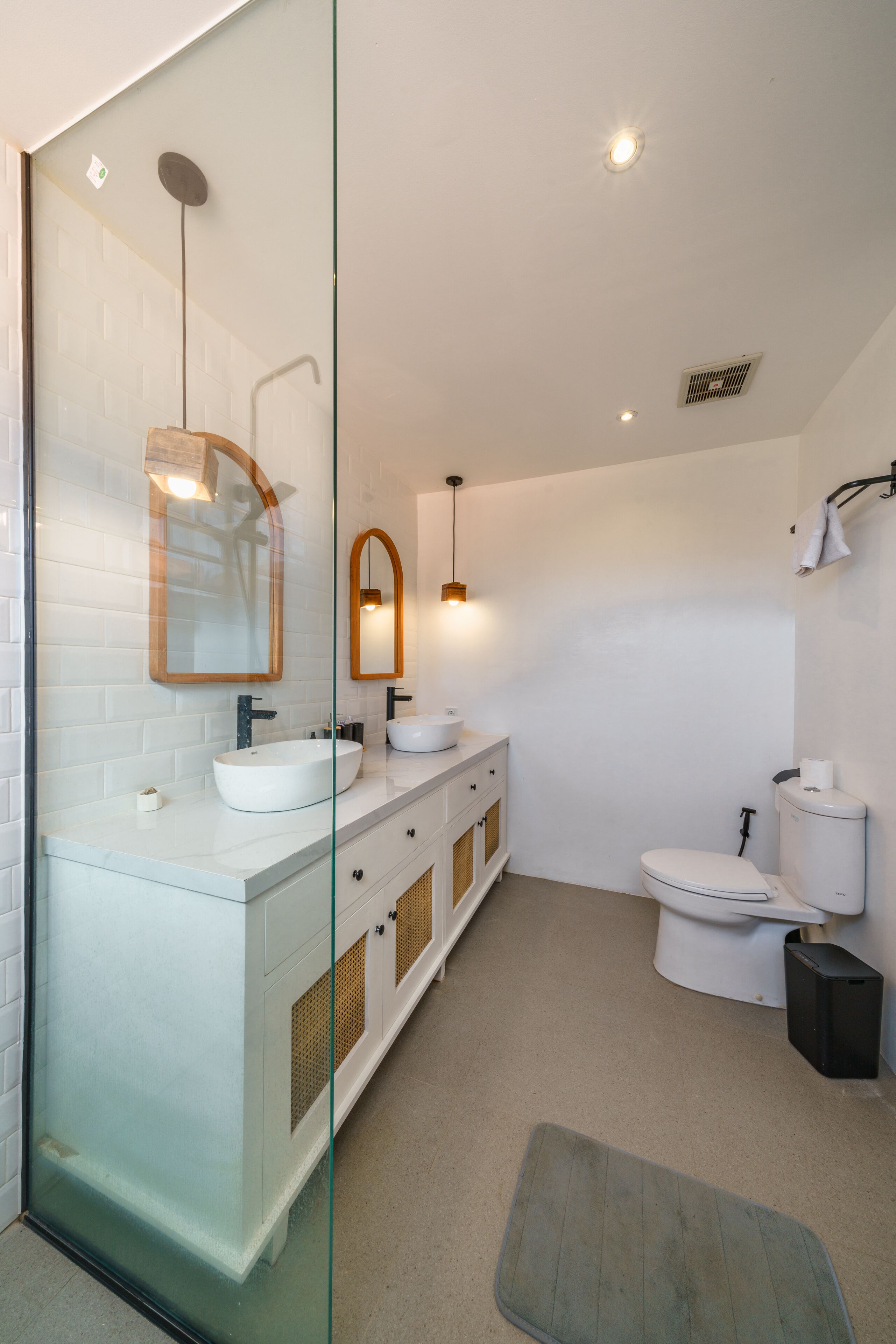 Une salle de bain moderne avec une douche à parois de verre, des accessoires blancs et un meuble-lavabo en bois.