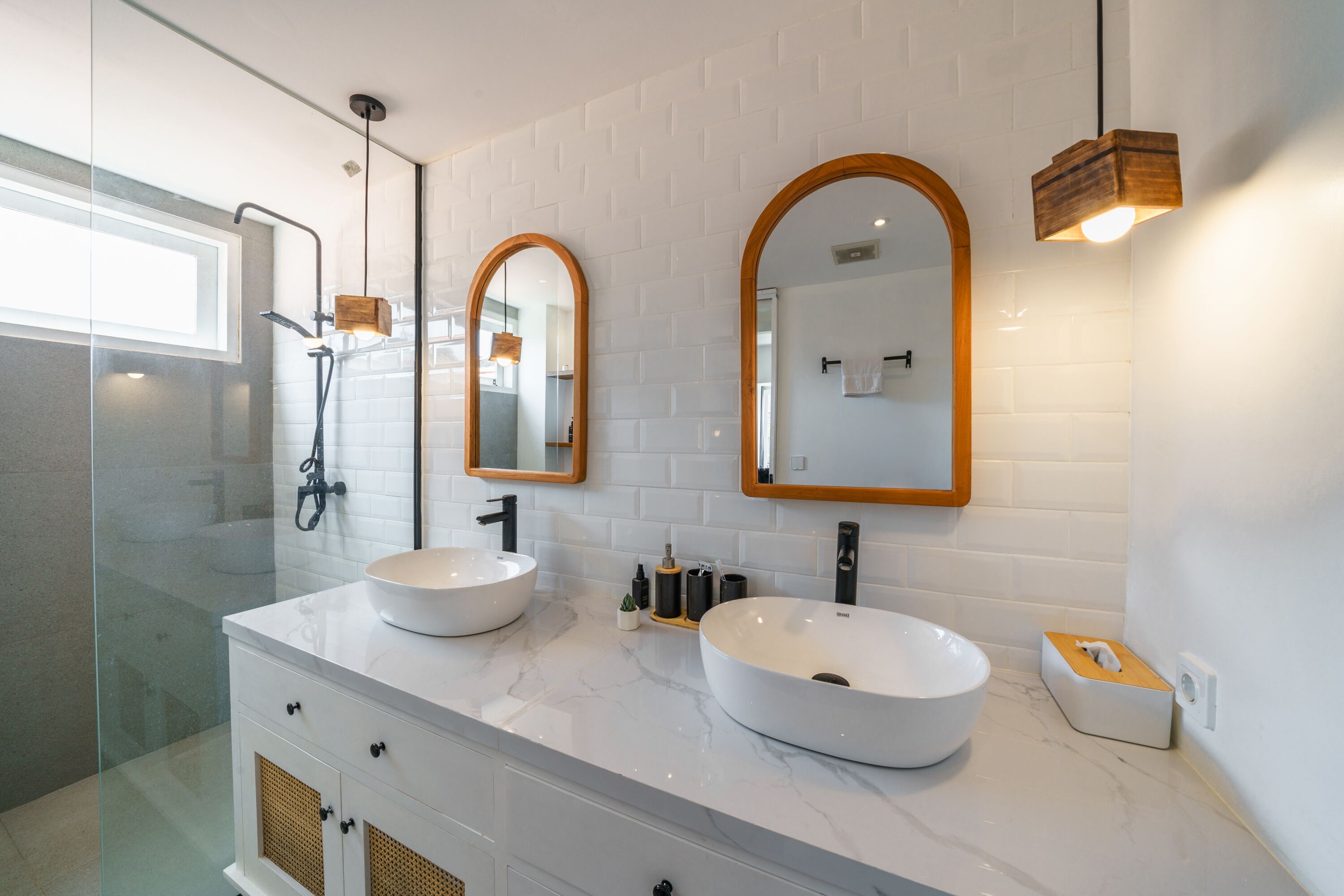 A modern bathroom with two sinks, a glass shower enclosure, and a white marble countertop.