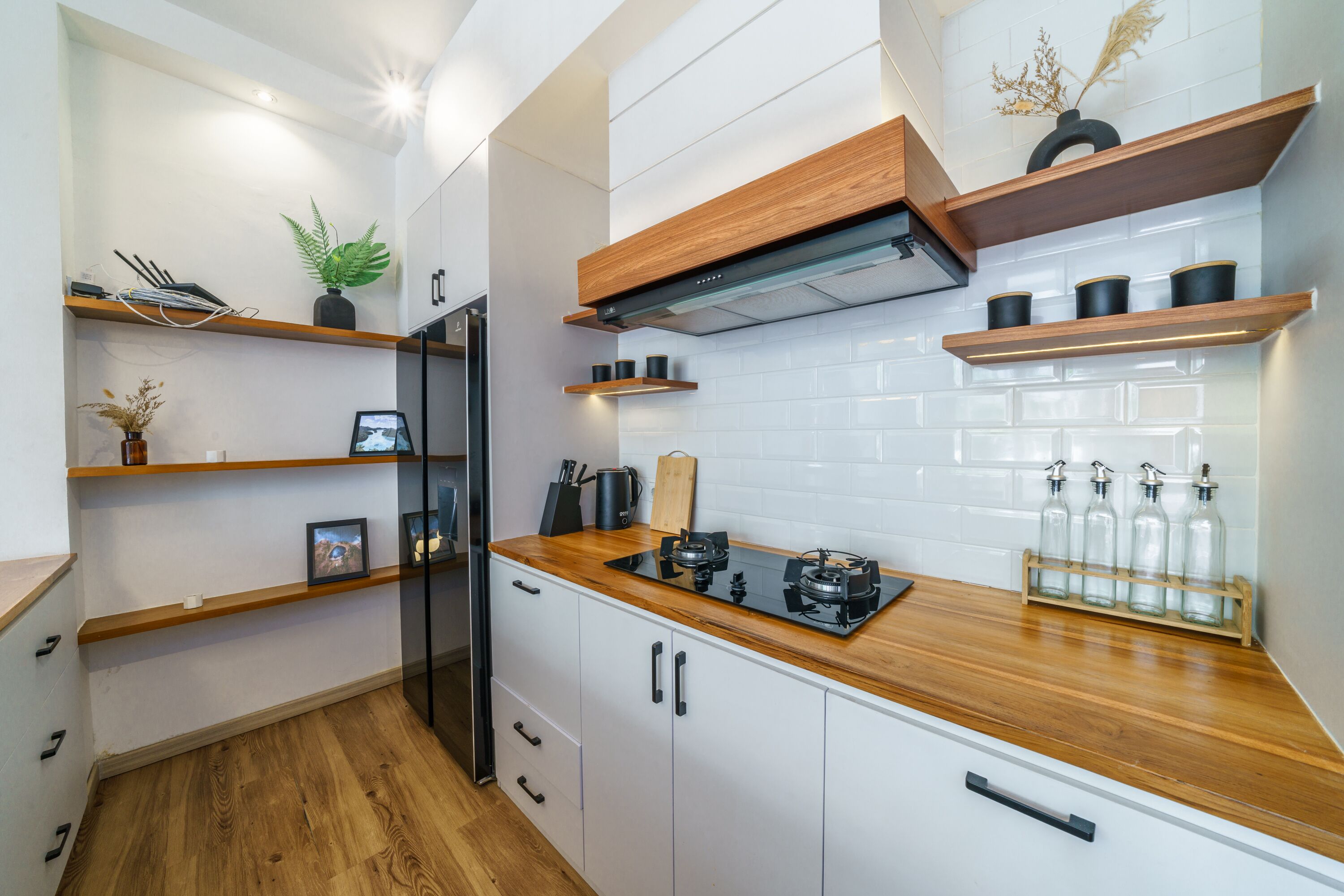 Una cucina moderna con mobili bianchi, piani in legno e scaffali integrati.