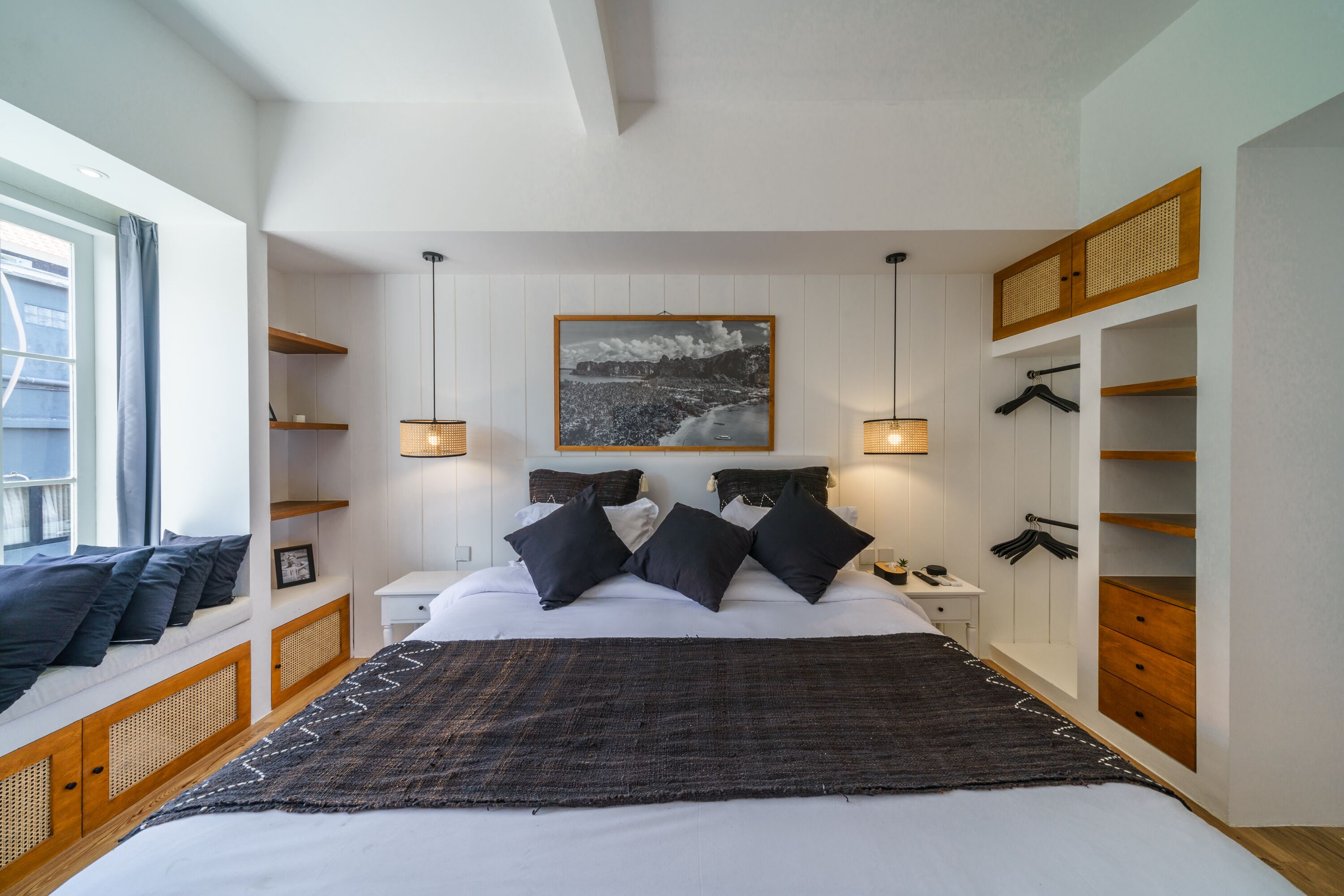 A bedroom with a large bed, bedside tables, a wardrobe, and a window with curtains.