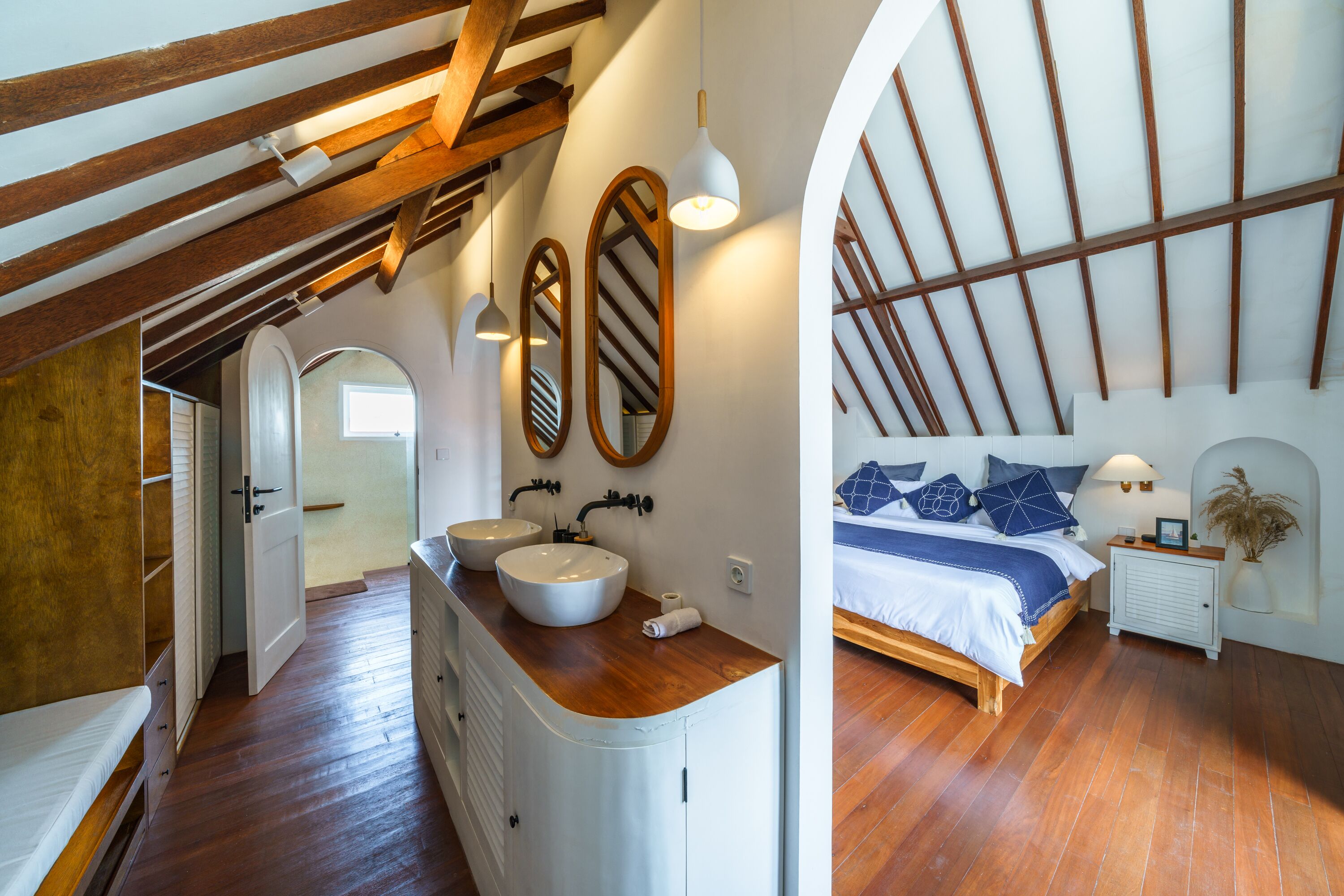 Une chambre avec un plafond en bois, un grand lit et une table de chevet.
