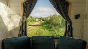Habitació amb vista per la finestra a un camp verd i arbres.