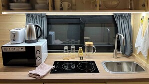 Una cuineta compacta amb torradora, bullidor, microones i un rentaplat.