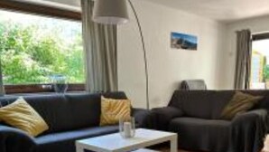Een woonkamer met een bank, een salontafel en een kamerkleed met dessin.