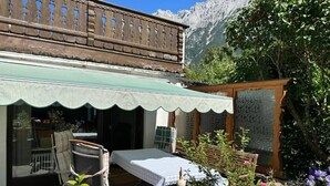 Een rustieke chalet met balkon, een klein terras en een tuin met klaprozen.