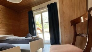 Een kamer met houten vloer, een bed, een stoel en een raam met gordijnen.