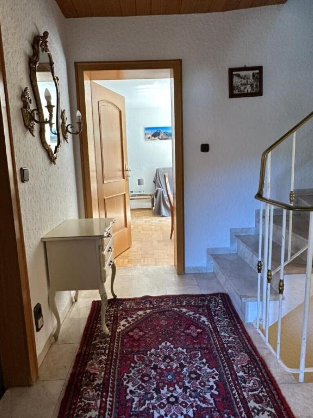 Ein Korridor mit Teppich, Spiegel, einer Tür zu einem Zimmer und einer Treppe.