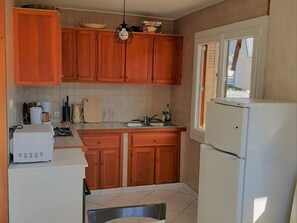 A compact kitchen with wooden cabinets, a white refrigerator, and a window providing natural light.